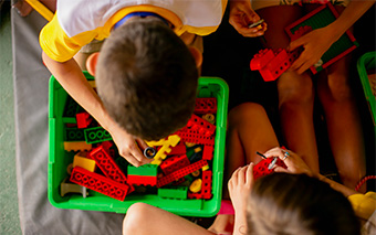 Descrição: Um grupo de crianças brincando com legos no chão, estimulando a criatividade e o pensamento crítico.