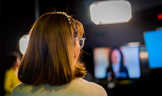Uma mulher assiste TV em uma sala de conferências enquanto curte o programa "Nossa História.
