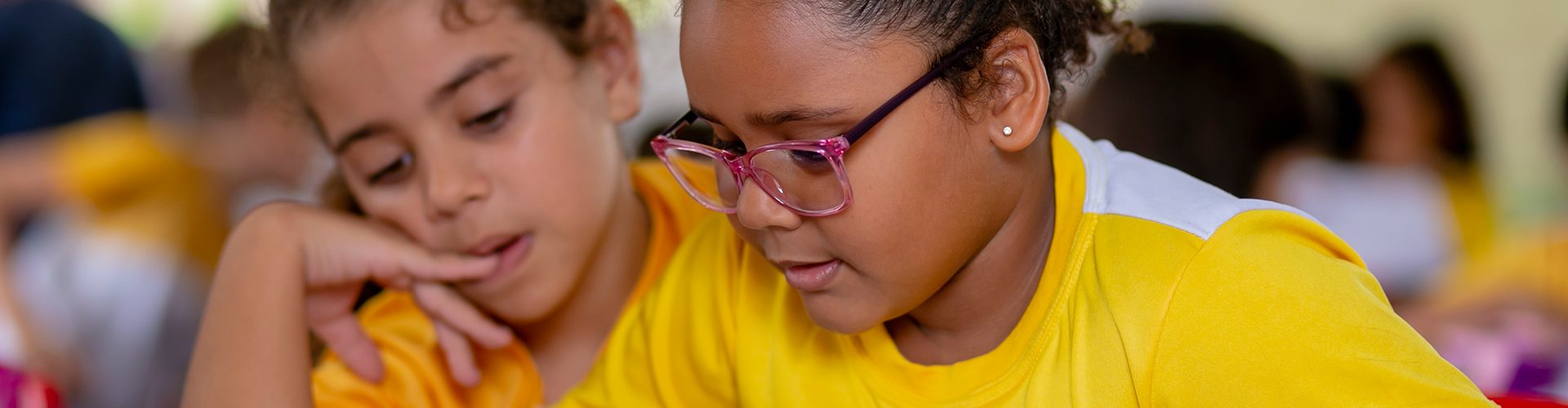Um grupo de crianças com camisas amarelas da Acelera Brasil está sentado em uma sala de aula.