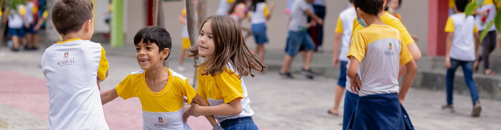 Um grupo de crianças vestindo camisetas amarelas e brancas participa das atividades do Minha Vida Educação Sociemocional.