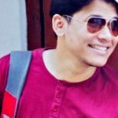 Rohit Thapa, um jovem de camisa marrom, sorri enquanto usa óculos escuros.