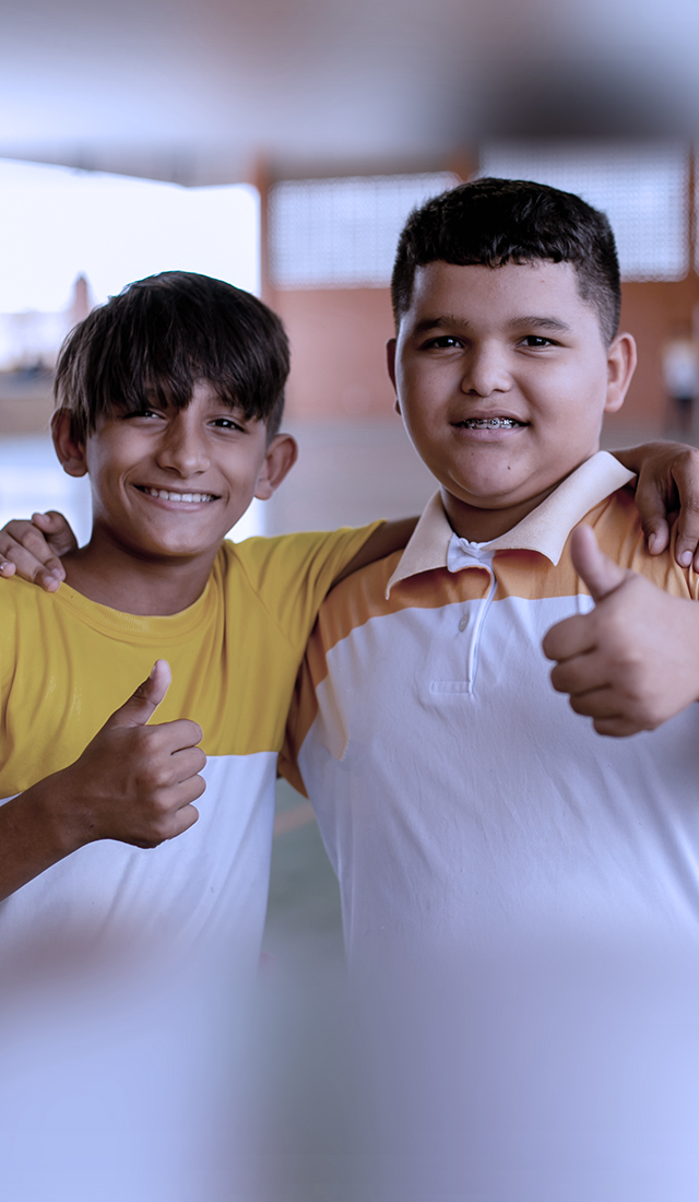 Two boys posing for a picture with thumbs up, supporting education.