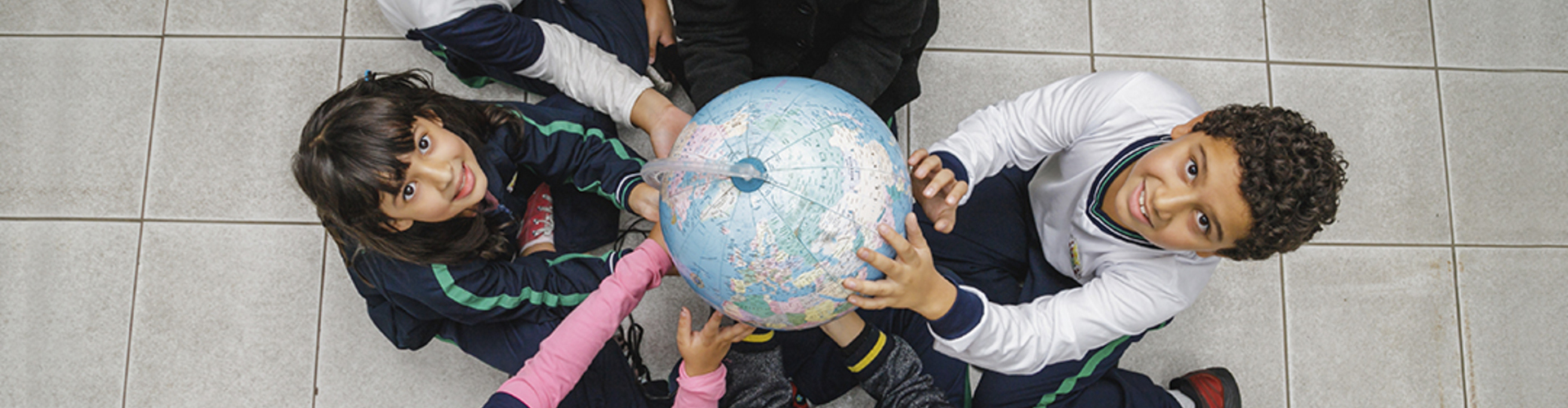Grupo de crianças segurando um globo em parceria com o Instituto Ayrton Senna.