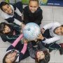 A group of children holding a globe as part of the Company Donation initiative in partnership with the Ayrton Senna Institute.
