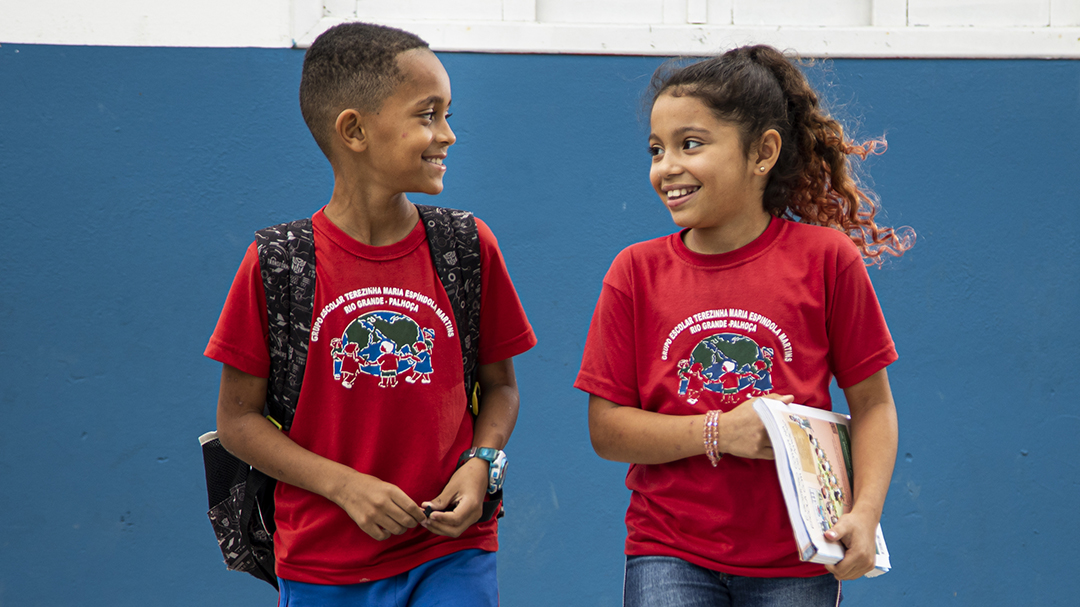 Two children in red t-shirts standing next to a blue wall, representing the impact of Company Donation.