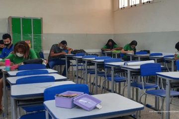 Um grupo de pessoas sentadas em carteiras em uma sala de aula participando dos Diálogos Socioemocionais, uma iniciativa do Instituto Ayrton Senna e Secretaria de Educação