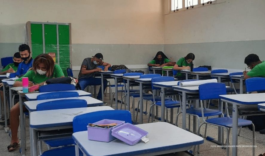 Um grupo de pessoas sentadas em carteiras em uma sala de aula participando dos Diálogos Socioemocionais, uma iniciativa do Instituto Ayrton Senna e Secretaria de Educação