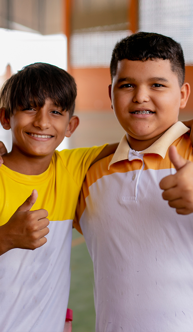 Dois meninos fazendo sinal de positivo, apoiando o Instituto Ayrton Senna e a educação.