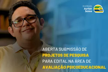 Um homem de óculos está diante de um cartaz anunciando uma convocatória para projetos de pesquisa na área de avaliação psicoeducacional.