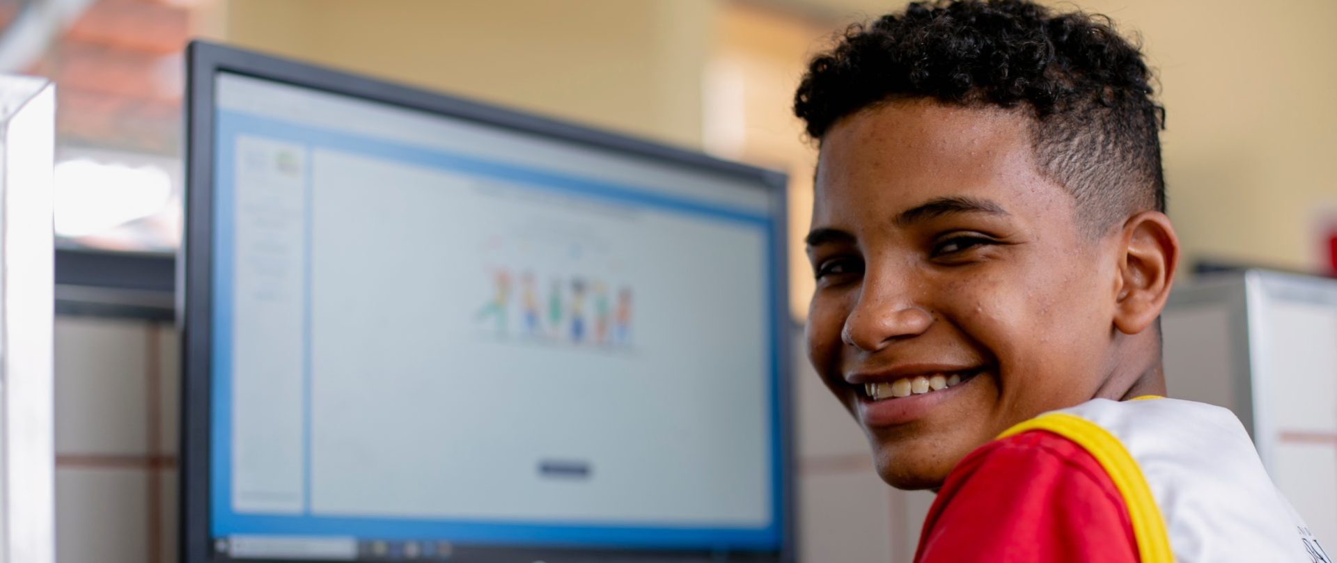 menino usando computador e sorrindo