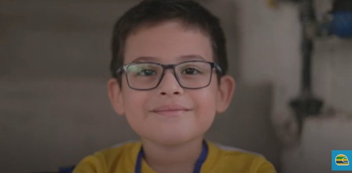 Um menino de óculos e camisa amarela participando de um estudo de caso.
