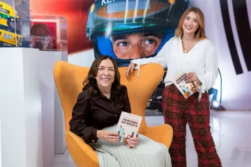 Thaís e Roberta Bento sorriem com o livro em mãos, Guia Para Família Parceira da Escola no Pós-pandemia, produto social da parceria entre o SOS Educação e o Instituto Ayrton Senna.
