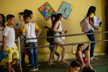 Um grupo de crianças no parapeito de uma escola, registro de soluções para diminuir os índices de abandono escolar.