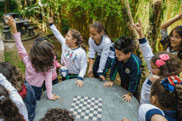 Um grupo de crianças jogando xadrez em um jardim.