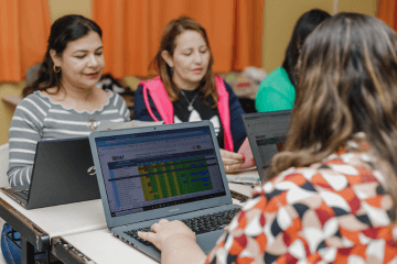 Um grupo de mulheres trabalhando em laptops em uma sala de aula.