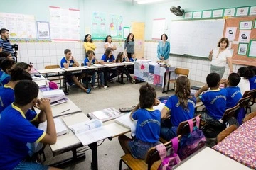 Um grupo de crianças está sentado em carteiras em uma sala de aula. Modelo de educação brasileira.