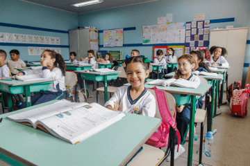 Um grupo de crianças sentadas em carteiras em uma sala de aula.