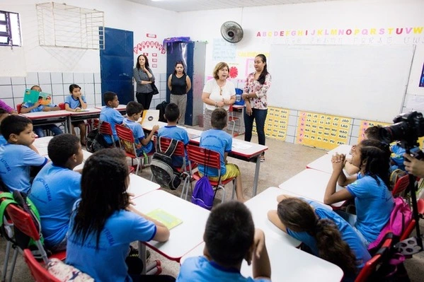 Um grupo de crianças está sentado em carteiras em uma sala de aula, desenvolvendo suas habilidades socioemocionais.
