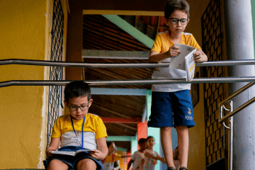 Dois meninos sentados na escada lendo um livro.