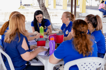 Um grupo de mulheres com camisas azuis sentadas à mesa.