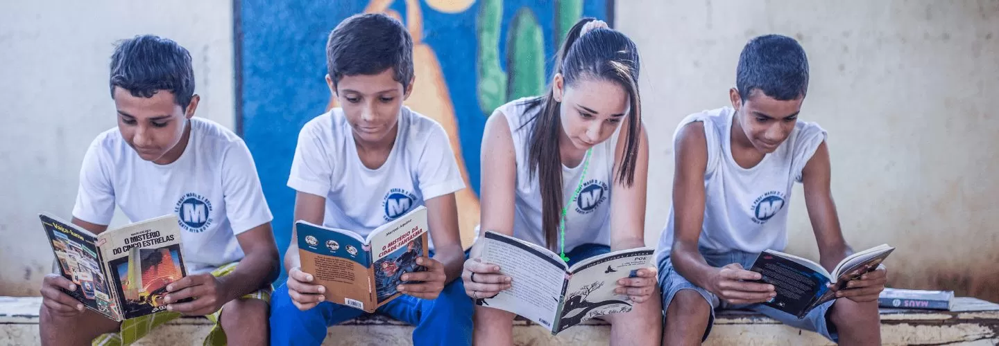 Um grupo de crianças lendo livros em um banco.