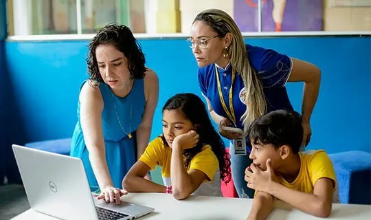 Um grupo de pessoas do Instituto Ayrton Senna olhando para um laptop em uma sala de aula.