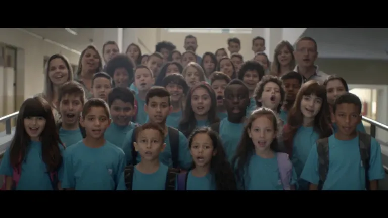 Um grupo de crianças do Instituto Ayrton Senna, vestindo camisas azuis, paradas em um corredor.