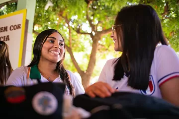 Um grupo de jovens está sentado à mesa com mochilas, mostrando suas habilidades de pensamento crítico.