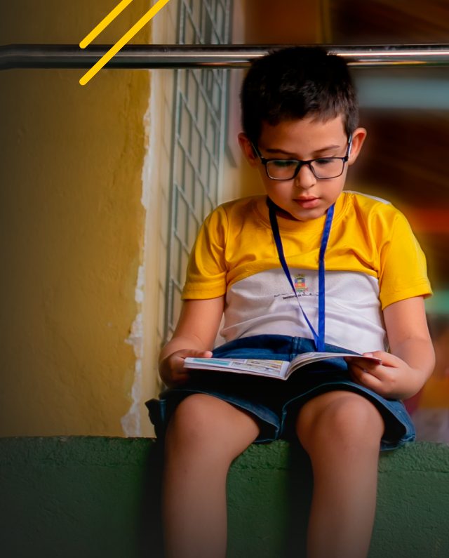 Um menino lendo um livro no Instituto Ayrton Senna.