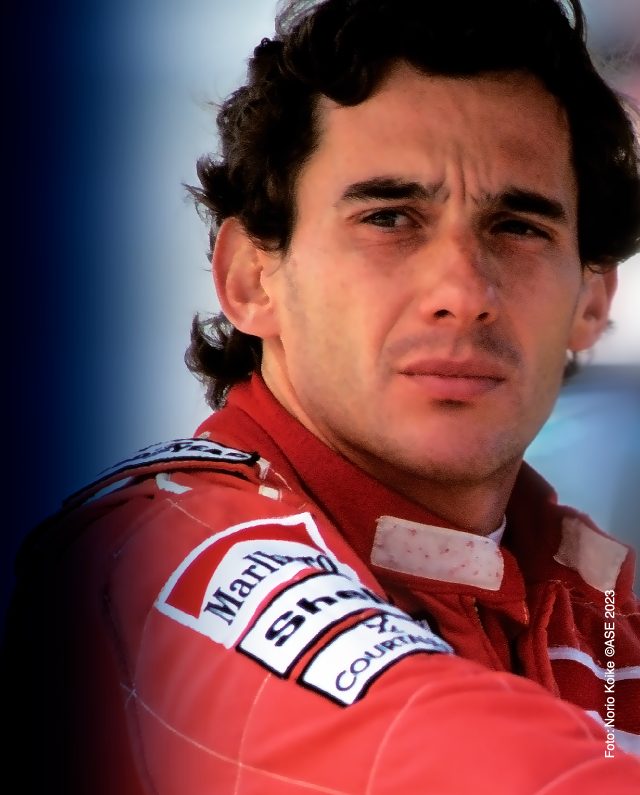 Retrato de um piloto de corrida vestindo um traje de corrida vermelho e branco do Instituto Ayrton Senna, olhando pensativamente para longe.