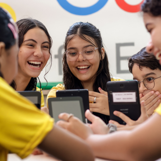 Grupo de crianças sorridentes, de camisas amarelas, usando tablets.