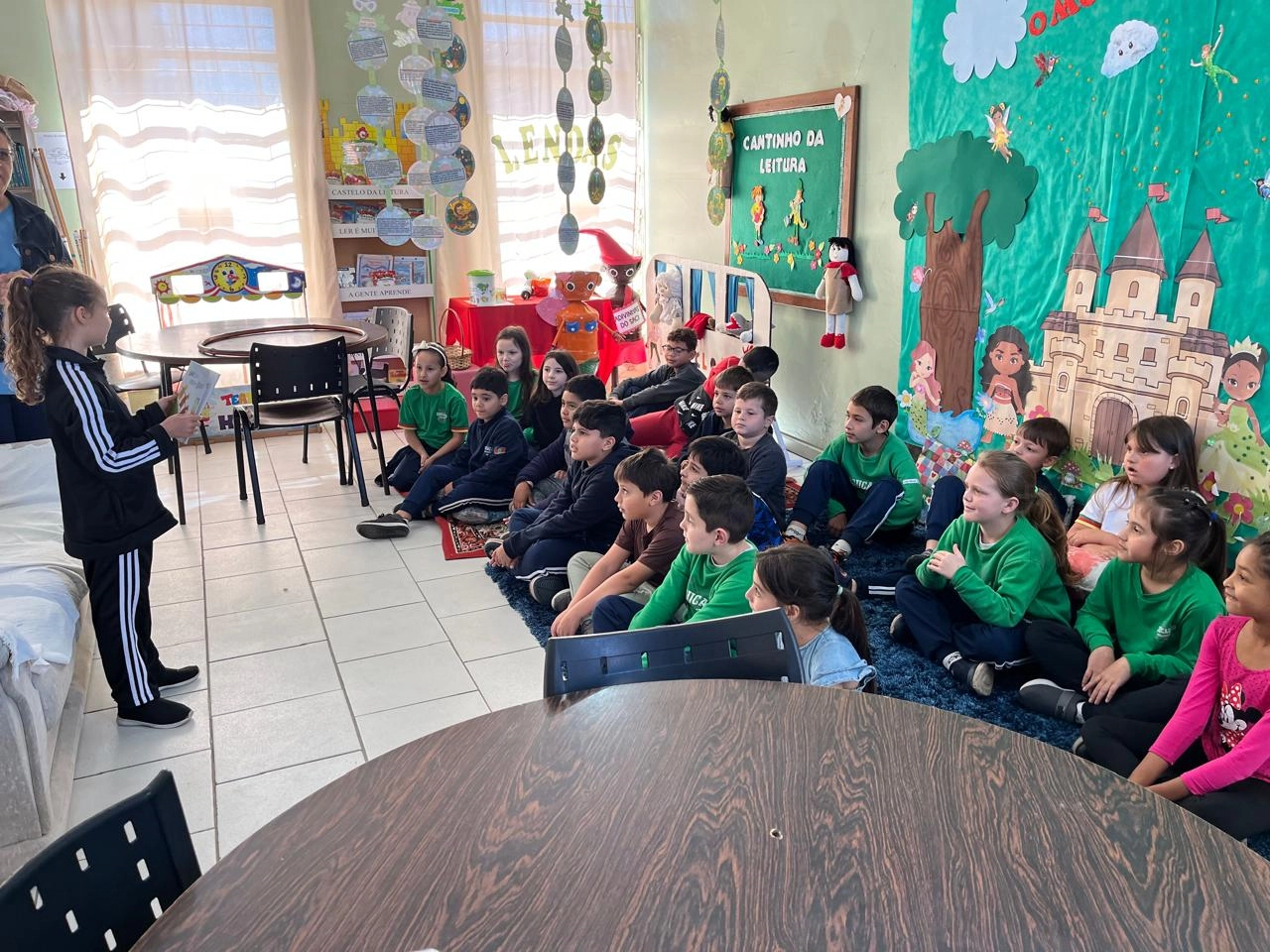 Crianças sentadas em biblioteca, ouvindo contação de histórias, em visita ao Rio Grande do Sul.