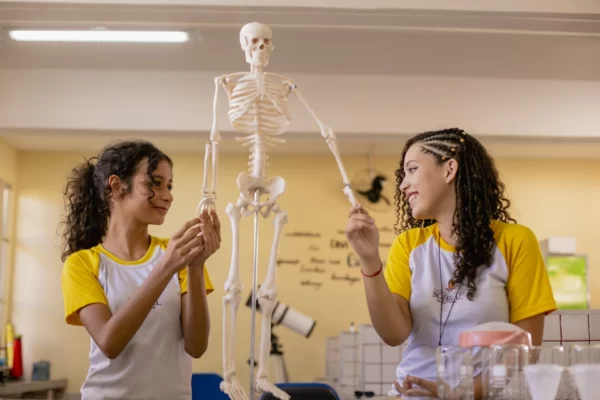 Estudantes explorando modelo anatômico em sala de aula, ilustrando como investimentos sociais em educação ampliam inovação, aprendizagem e impacto corporativo.