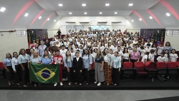 Manaus - Plano Anual - Grande grupo de pessoas posando para uma foto em um auditório, algumas uniformizadas, outras segurando uma bandeira do Brasil, comemorando um evento especial com o processo de Rascunho automático da organização.