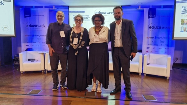 Quatro pessoas posando no palco em frente ao logotipo da Educa Week 2026.