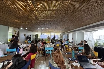 Um grupo de pessoas participando de um seminário do Instituto Ayrton Senna sobre Educação Integral em uma sala com teto de ripas de madeira.