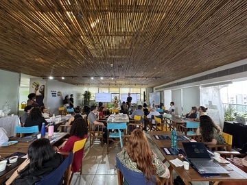 Um grupo de pessoas participando de um seminário do Instituto Ayrton Senna sobre Educação Integral em uma sala com teto de ripas de madeira.
