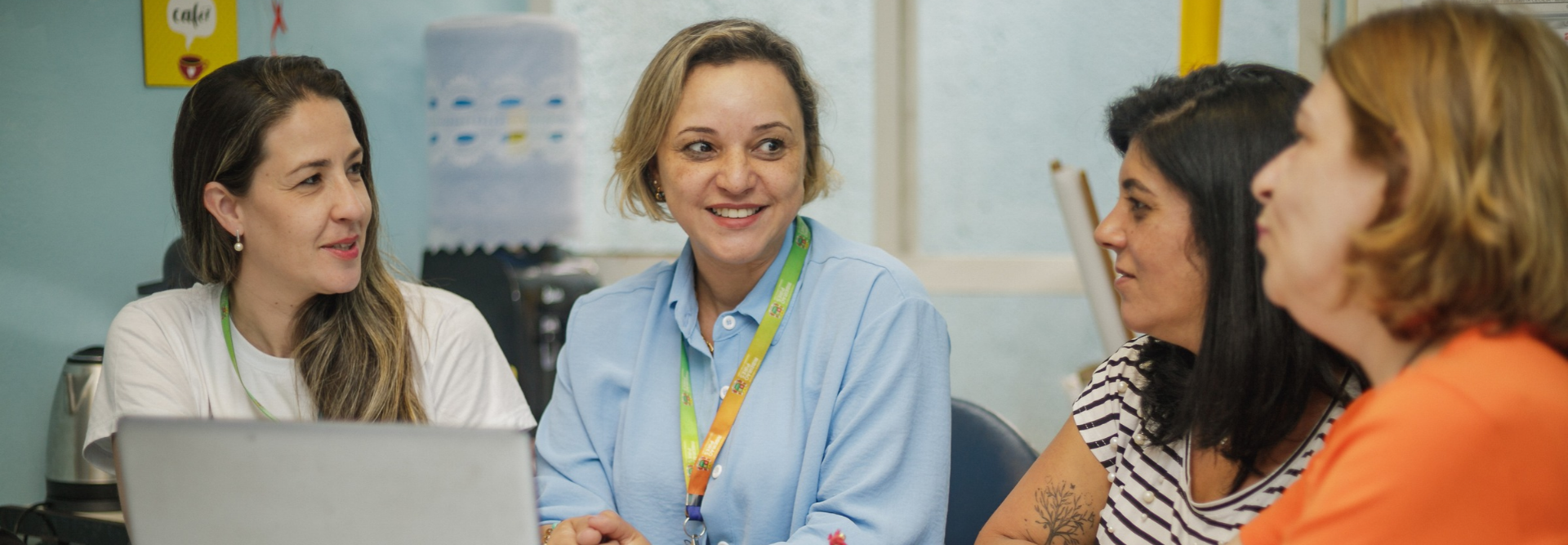 Quatro mulheres da Cátedra da UNESCO sentadas juntas e conversando em um espaço de escritório.