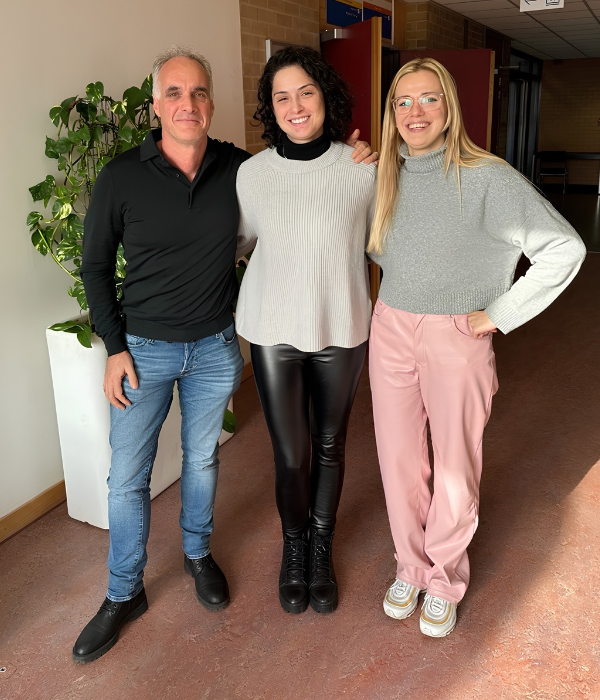 Três pessoas estão juntas em um corredor, sorrindo para uma foto da Cátedra Instituto Ayrton Senna.